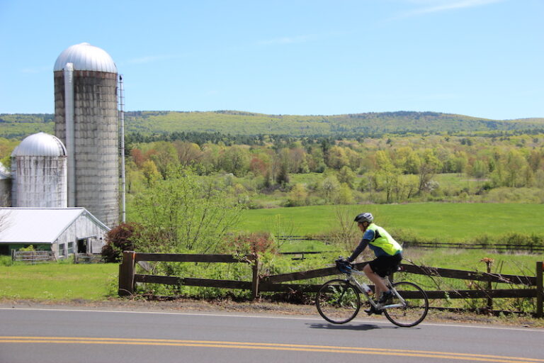 Man on a bicycle food tour in Spring near farm and silo