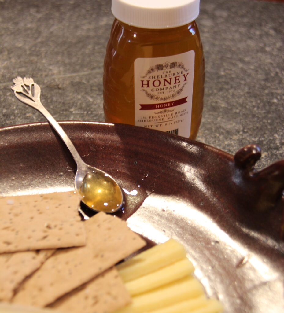 A spoon of honey in a plate full of crackers