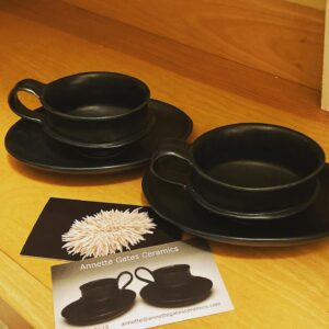 Two handmade black ceramic espresso cups and saucers