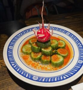 A plate of food with cucumbers and carrots on it.