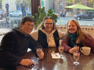 three people smiling eating chocolate mousse in a cafe