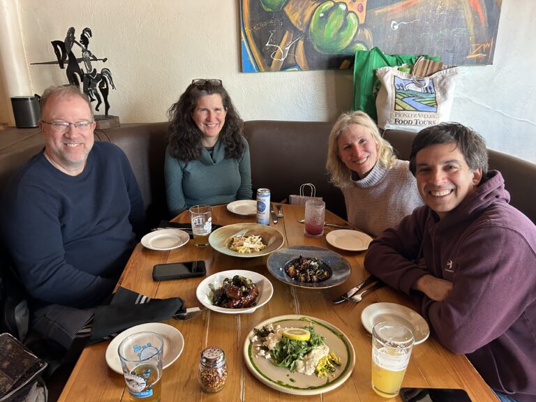 Food tour group in booth with a selection of dishes and local craft beer