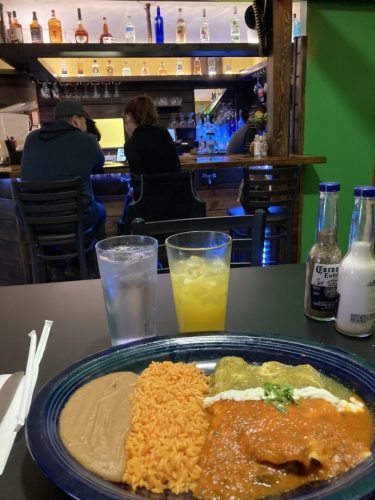 Mexican enchiladas red green sauce agua fresca decorative bottles along bar behind